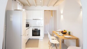 Une cuisine moderne avec des meubles blancs, un four encastré et un coin repas comprenant une table et des chaises en bois.