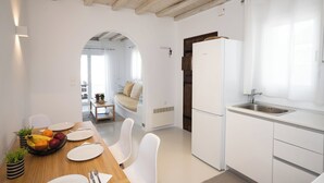 Une cuisine moderne avec des meubles blancs, un réfrigérateur encastré et une fenêtre avec des rideaux.