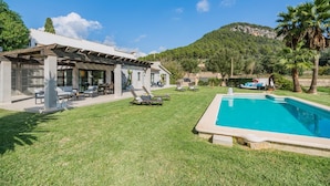 Une maison moderne avec une piscine, un espace salon extérieur et une vue sur une montagne.