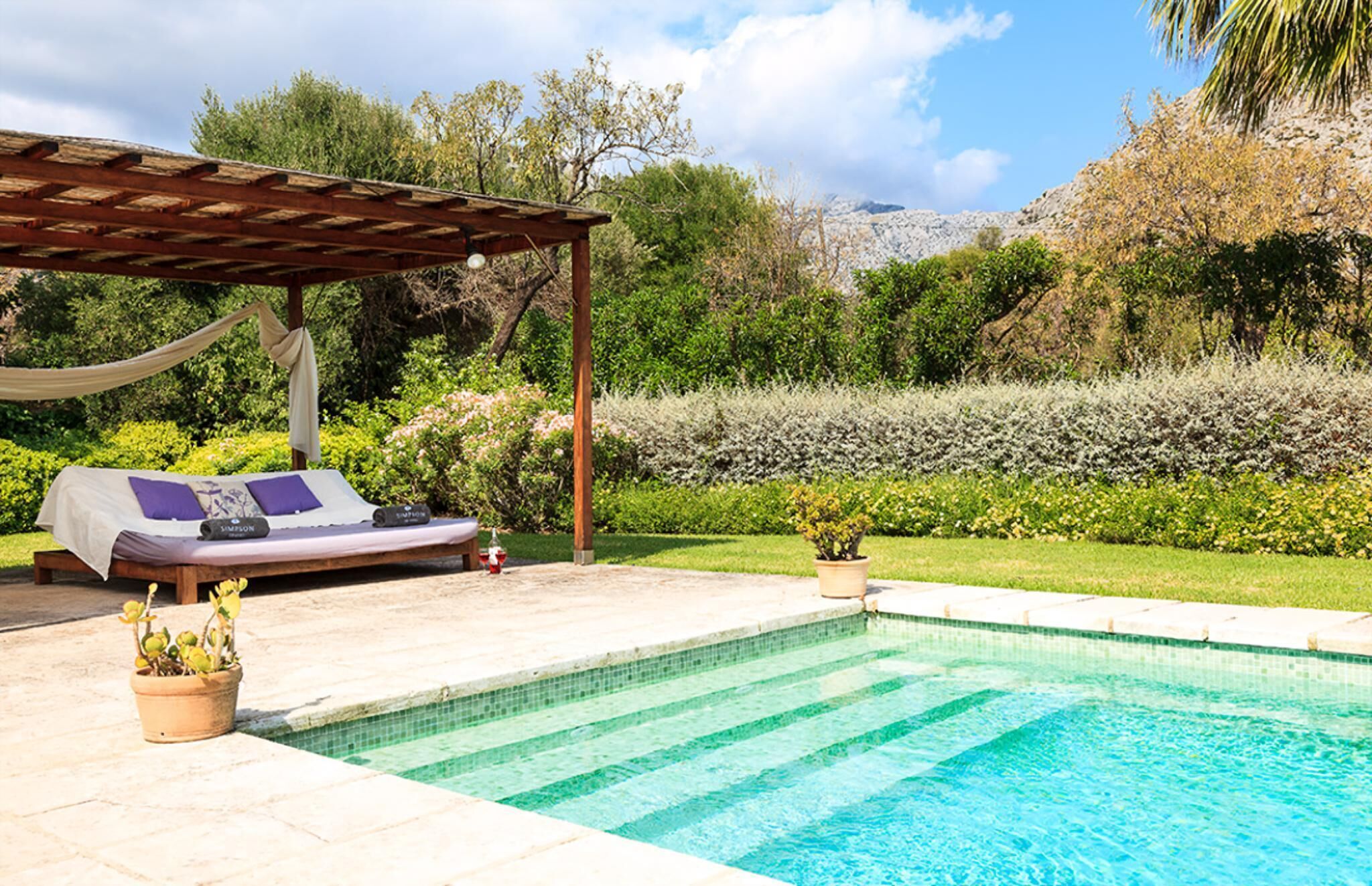 A poolside area with a wooden pergola, a lounge chair, and a small pool.
