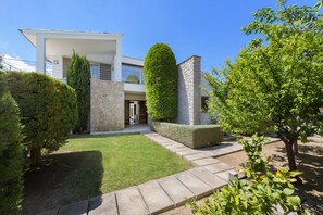 Une maison moderne avec une pelouse bien entretenue, un chemin de pierres et des haies soigneusement taillées.