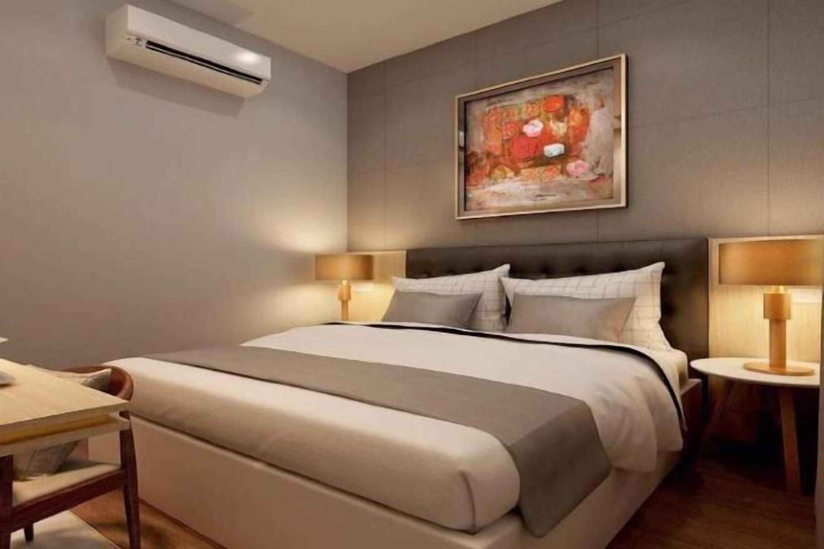 Una camera d'albergo con un letto, comodini, un condizionatore d'aria e un quadro appeso al muro.