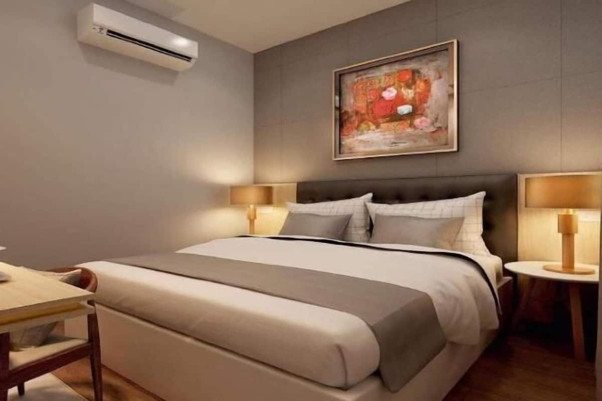 Ein Hotelzimmer mit Bett, Nachttischen, einer Klimaanlage und einem Bild an der Wand.
