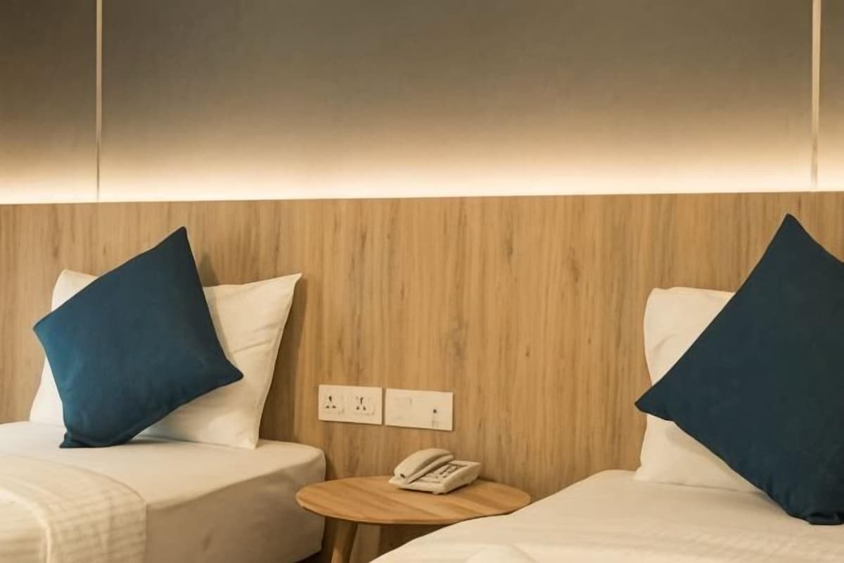 A hotel room with two beds, a small round table with a phone, and a wooden panel wall.