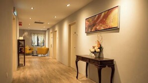 A hotel hallway with wooden flooring, a dark wooden console table with flowers, and a painting on the wall. - Hotel CIQ, Jalan Trus (Johor Bahru)