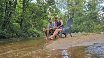 Deux personnes se détendent au bord d’un ruisseau, dans un cadre naturel.