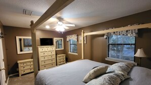 Une chambre à coucher comprenant un lit, une commode, une coiffeuse et un ventilateur de plafond.