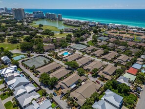 Un quartier résidentiel avec des maisons, un court de tennis et une vue sur l’océan.