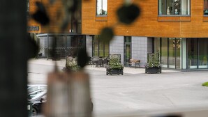 A modern building with a wooden facade, large windows, and outdoor seating areas. - Hotell Säsong - Boden Business Park (Boden)