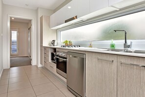 A modern kitchen with a built-in dishwasher, oven, and a large window above the sink.
