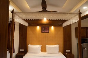 Relax in a traditional room with a four-poster bed, wooden nightstands, and a ceiling fan.