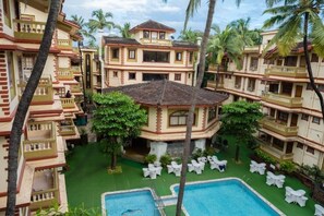 Experience the tranquil atmosphere of our central courtyard, featuring a swimming pool surrounded by lounge chairs and palm trees.