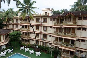 Experience the charm of this traditional hotel, featuring a central entrance and balconies on each floor, with a pool and lush garden nearby.