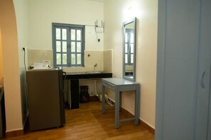 Compact kitchen area with a refrigerator, sink, and table, offering a convenient space for meal preparation.