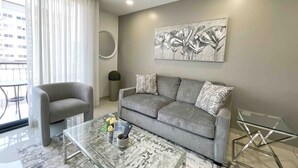 Un salón moderno con un sofá gris, una mesa de centro de vidrio y un cuadro en la pared.