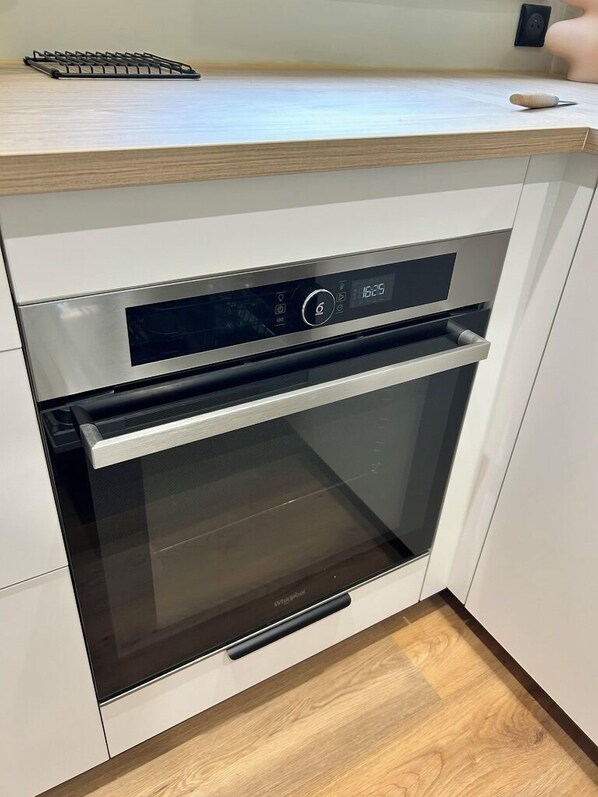A modern kitchen with a built-in oven and microwave, a wooden countertop, and a black handle.