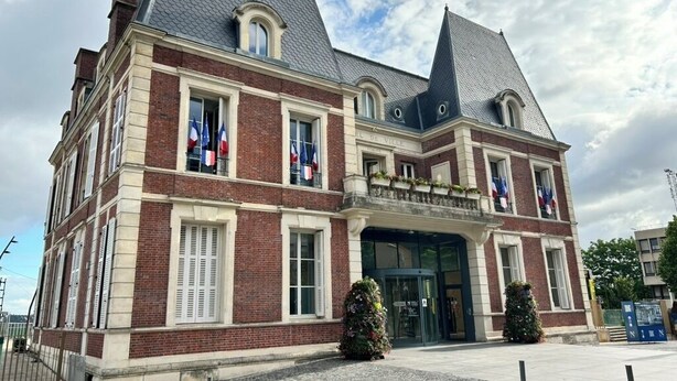 Een historisch gebouw met een symmetrische gevel, grote ramen en een opvallende ingang.