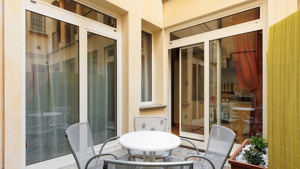 A small patio area with a round table and four chairs, large sliding glass doors, and a potted plant. - Bertiera Family Duplex by Wonderful Italy (Bologna)