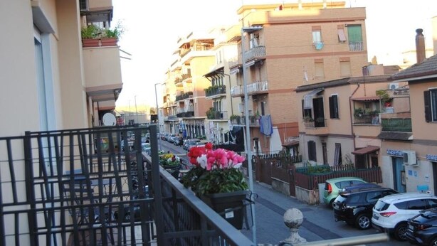 A residential street with multi-story buildings, balconies, and parked cars.