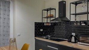 Une cuisine moderne avec un dosseret de carreaux noirs, une hotte noire et des étagères noires.