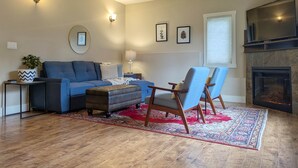 A living room with a sofa, two armchairs, a coffee table, a fireplace, and a ceiling fan.