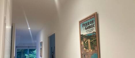 Un pasillo con un cartel de Perros-Guirec, un tablón informativo turístico y vistas de una habitación con cama y ventana.