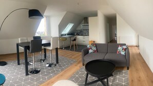Um apartamento moderno com área de jantar, sofá, mesa de centro e cozinha ao fundo.