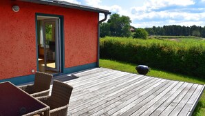 A wooden deck with wicker furniture and a glass door leading to a room.