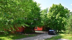 A gravel path leading to a red building with a car parked nearby.