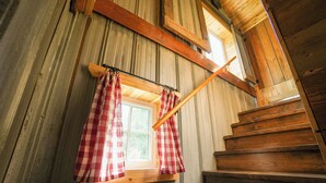 Un escalier en bois avec une fenêtre ornée de rideaux à carreaux rouges et blancs.