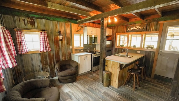 L’intérieur d’un chalet rustique comprend une cuisine, un coin repas et un espace détente.
