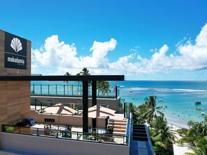 A Makadamia Prime hotel with a pool area, outdoor seating, and a view of the beach and ocean.