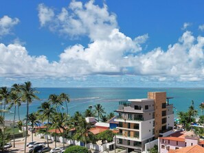 A modern multi-story building with balconies overlooking a beach and ocean. - TEKATETU Hotels&Flats - Makadamia (Ipojuca)