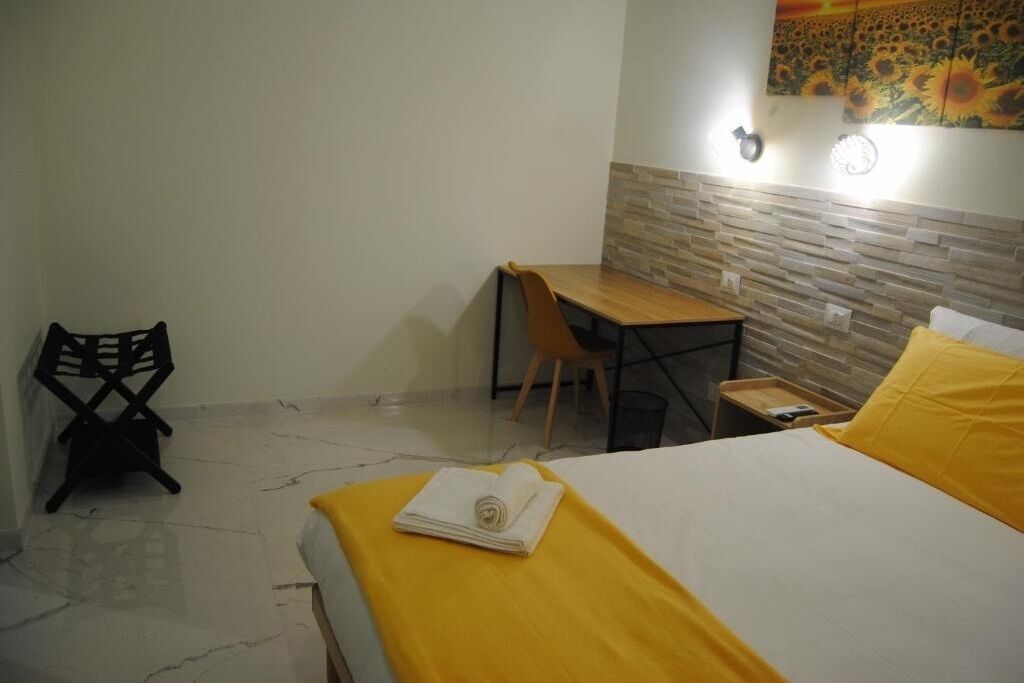 A hotel room with a bed, a desk, a chair, and a small table.