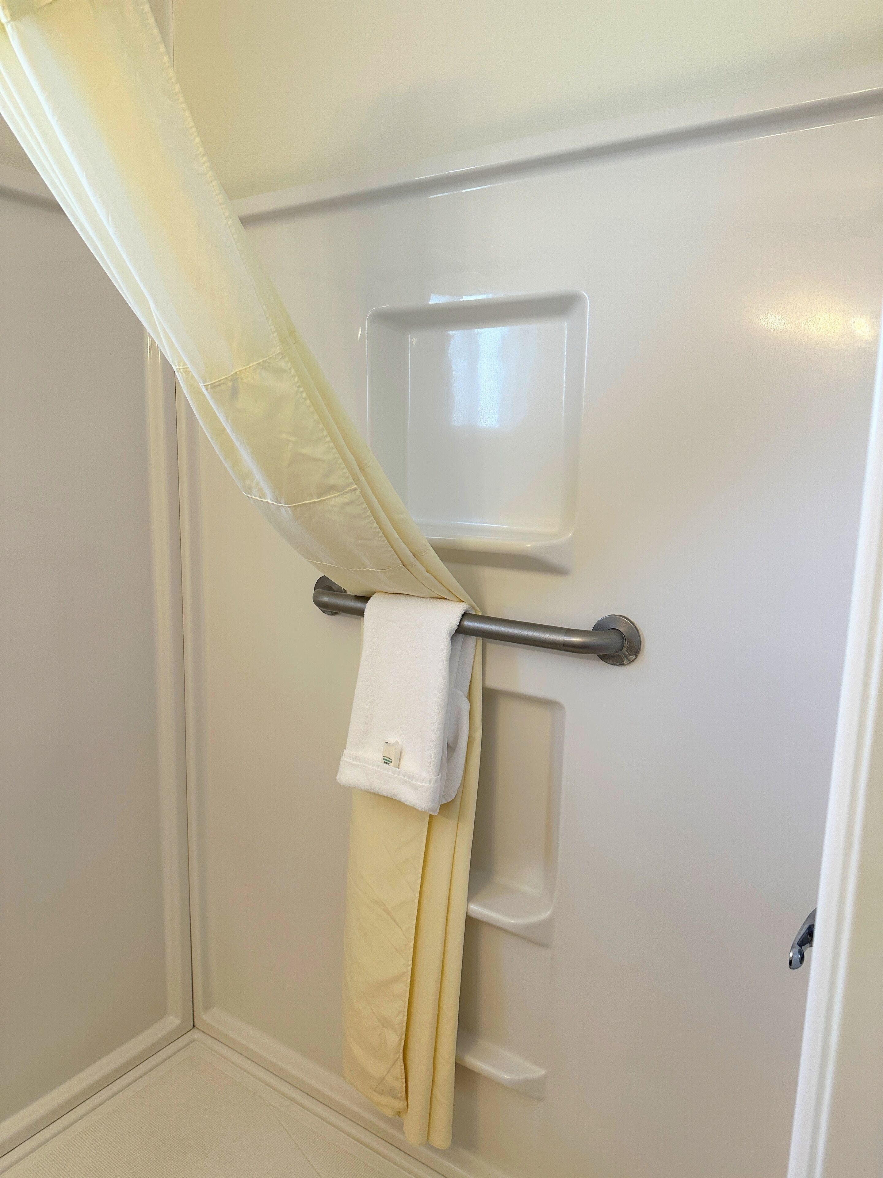 A bathroom with a towel rack, a shower curtain, and a towel hanging on the rack.