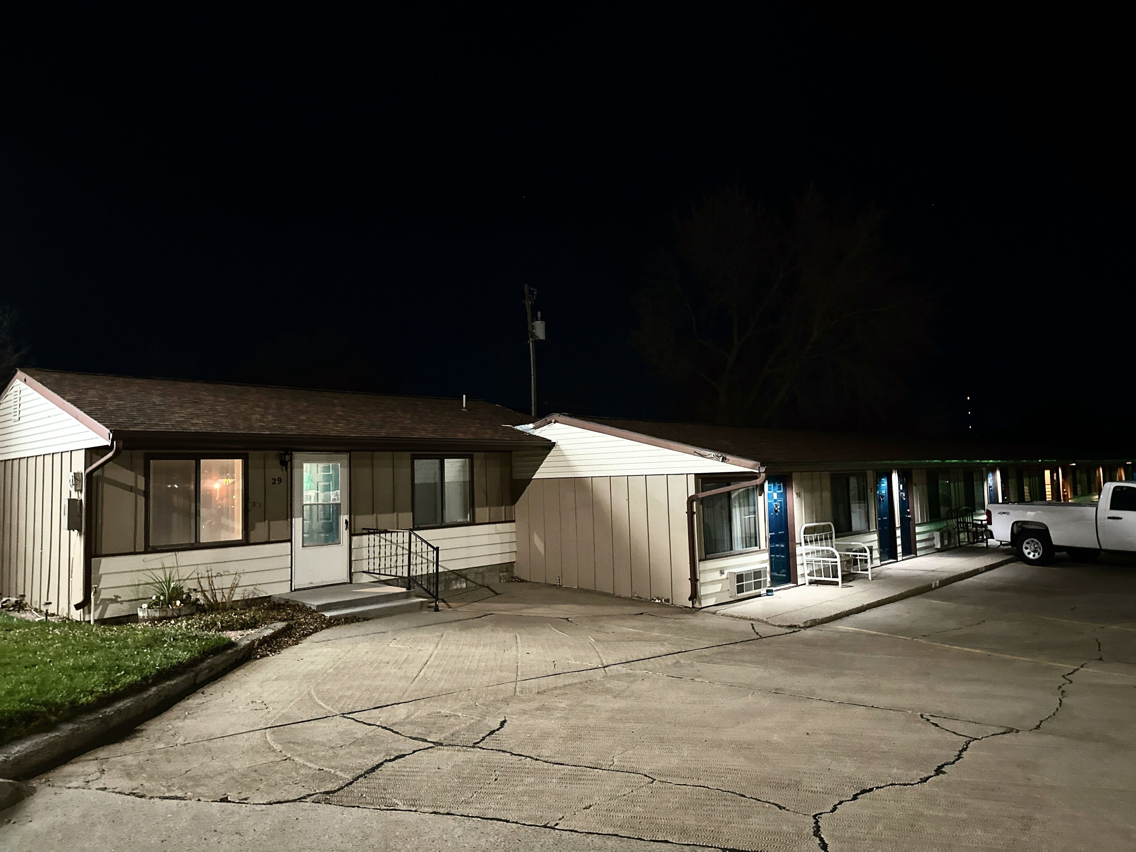 Un motel de planta baja, con un espacio de estar cubierto al aire libre y un estacionamiento.