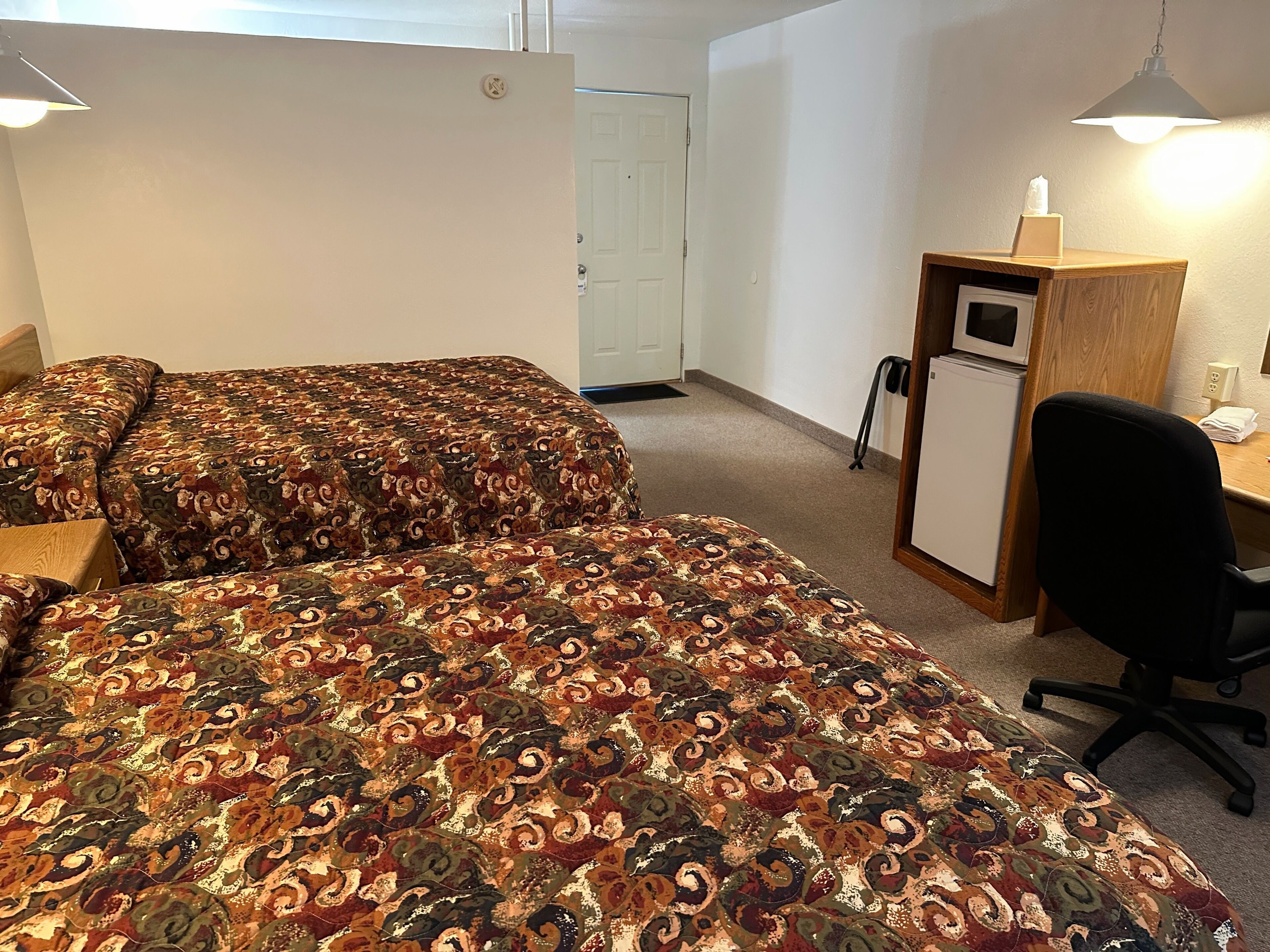 A room with two beds, a desk, and a chair.
