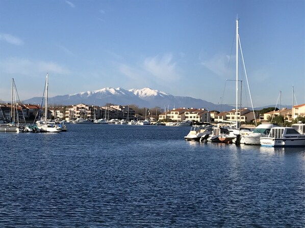 Eine Marina mit vertäuten Booten, einem klaren Himmel und einem Gebirge im Hintergrund.