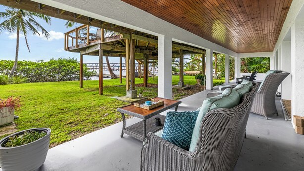 A covered outdoor seating area with wicker furniture and a wooden ceiling. - Dockside studio in Jensen Beach (Jensen Beach)