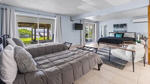 A modern bedroom with a large bed, a sofa, and a TV. - Dockside studio in Jensen Beach (Jensen Beach)