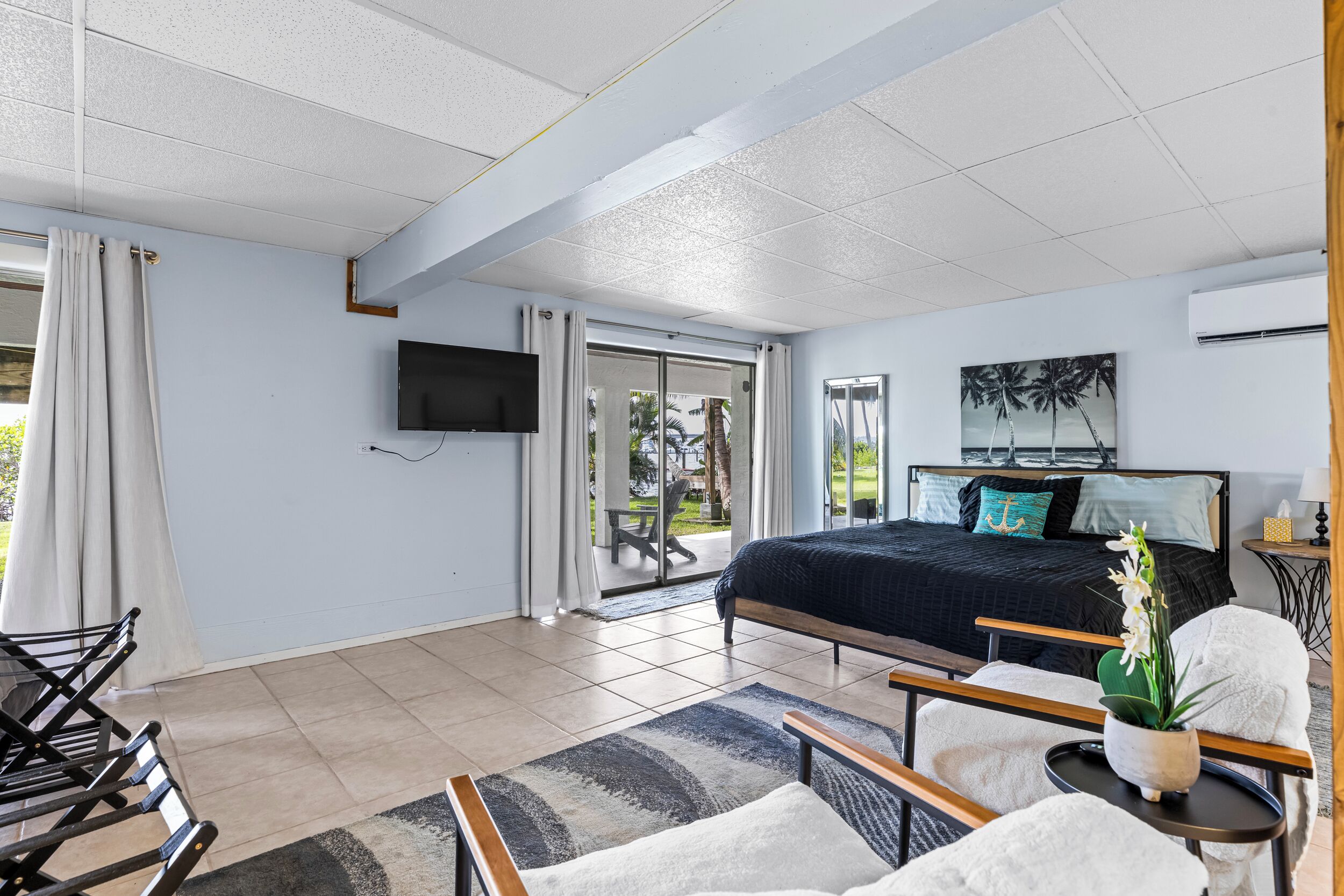 Une chambre avec un lit, une télévision, un balcon et une vue sur des palmiers.