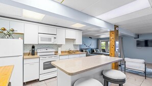 A modern kitchen with white cabinets, a central island with stools, a microwave, oven, and a coffee machine. - Dockside studio in Jensen Beach (Jensen Beach)