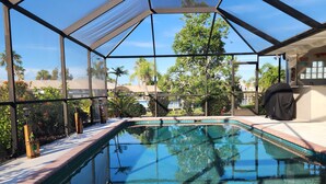 Ein Poolbereich mit Glasveranda, Pool und einer Terrasse mit Stuhl.