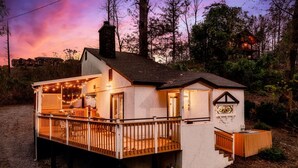 A small, single-story wooden cabin with a deck, a chimney, and a sign indicating a restaurant. - Outlander Couples Cottage/Walk to Downtown/Hot Tub (Gatlinburg)