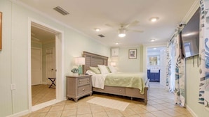 A bedroom with a bed, nightstands, a ceiling fan, and a view into the bathroom.