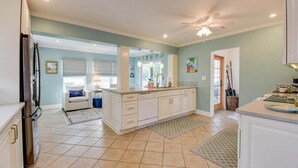 A spacious kitchen with white cabinets, a large island, and a ceiling fan.