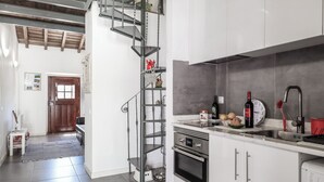 Una cocina moderna con armarios blancos, electrodomésticos de acero inoxidable y una escalera de caracol.