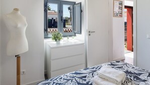 Un dormitorio con cama, cómoda, tocador con espejo y un maniquí.