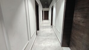 A long, narrow hallway with white walls and a marble floor. - Serendipity by the Ganges (Varanasi)