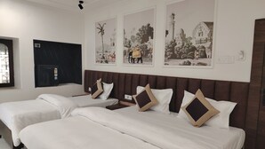 A hotel room with two beds, a refrigerator, and wall art depicting historical scenes. - Serendipity by the Ganges (Varanasi)